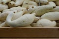 Close-up of a wooden table with a variety of white gourds resting inside a cardboard box