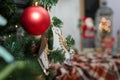 Close up of wooden toy skates and red bulb hanging on fir tree branches. Blurry Santa Claus toy and lantern with warm lights Royalty Free Stock Photo