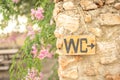 Close up of a wooden WC sign with an arrow hanging from a stone wall of a bathroom at a wedding Royalty Free Stock Photo