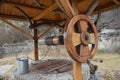 A close-up of a wooden well with a wooden well pulley, wheel and a metal bucket