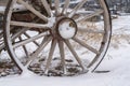 Close up of the wooden wheel of an old wagon against a snowy terrain in winter Royalty Free Stock Photo