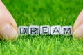 Word DREAM written in metal letters laid on grass and held between the fingers of a woman. Concept of aspiration, hope background Royalty Free Stock Photo