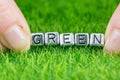 Word GREEN written in metal letters laid on grass and held between the fingers of a woman. Concept of ecology background Royalty Free Stock Photo