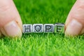 Word HOPE written in metal letters laid on grass and held between the fingers of a woman. Concept of aspiration, hope background Royalty Free Stock Photo