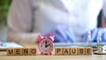 Word menopause made of wooden blocks in raw and pink alarm-clock