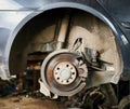 Worker changing car wheel in garage, auto servicing center.