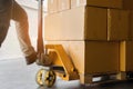 Close up worker with hand pallet truck and package boxes on pallet