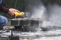 Worker hand using grinder cutting turf stone block for paving sidewalk in public gardening area Royalty Free Stock Photo