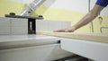 Close-up of worker holds wooden board on woodworking machine. Action. Worker in gloves processes wooden board on Royalty Free Stock Photo