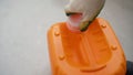 A hand opens the lid of a plastic canister. Close-up of a worker opening an orange canister.