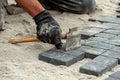 Worker laying pavers on sand base for pathway construction