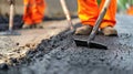 Close-up of worker's hands with shovel applying asphalt on road construction site. Royalty Free Stock Photo