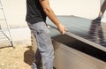 Close-up of a worker's hands tying a stack of solar panels with orange webbing