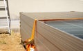 Close-up of a worker\'s hands tying a stack of solar panels with orange webbing