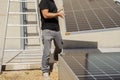 Close-up of a worker\'s hands tying a stack of solar panels with orange webbing