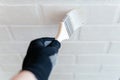 Close-up of a worker& x27;s hand with a brush painting a brick wall with white paint. Royalty Free Stock Photo