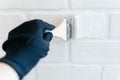 Close-up of a worker& x27;s hand with a brush painting a brick wall with white paint. Royalty Free Stock Photo