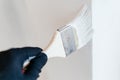 Close-up of a worker& x27;s hand with a brush painting a wall with white paint. Royalty Free Stock Photo