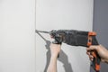 Close-up of a worker& x27;s hands holding a puncher. A young man drills holes in the wall with a hammer drill. The master Royalty Free Stock Photo