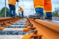 A close-up of a workers boot on railway tracks with maintenance crew in the background, showcasing construction safety and Royalty Free Stock Photo