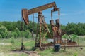 Working pump jack pumping crude oil at oil drilling site in rural USA