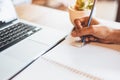 Close up of working woman hand using laptop computer and writing letter on notebook paper in office desk. Business and people Royalty Free Stock Photo