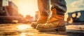 Close-Up of Worn Work Boots on Construction Site with Sunset in Background. Royalty Free Stock Photo