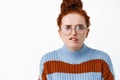 Close up of worried and troubled redhead woman in glasses, frowning and biting lip puzzled, have proble, staring