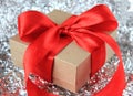 Close-up wrapped vintage gift box with red ribbon bow on silver sparkly background
