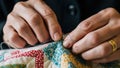 Elderly hands hand-stitching a colorful patchwork quilt. Royalty Free Stock Photo