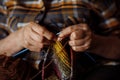 Unrecognizable woman hands of elderly woman, spoke knitting colorful checkered clothes. Making new scarf or sweater Royalty Free Stock Photo