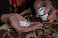 Close-up of wrinkled hands of grandmother pouring pills from a jar