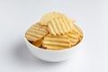 Close up of Wrinkled Wavy Potato Chips in white ceramic bowl, Popular Ready to eat crunchy, salty pale-yellow color over white Royalty Free Stock Photo