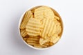 Close up of Wrinkled Wavy Potato Chips in white ceramic bowl, Popular Ready to eat crunchy, salty pale-yellow color over white Royalty Free Stock Photo