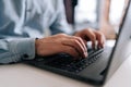 Close-up wrinkly hands of unrecognizable senior older businessman typing on laptop keyboard. Closeup cropped shot of