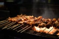 Close-up of yakitori skewers sizzling on a charcoal grill, with smoke rising and flames flickering in the background