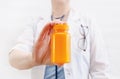 Close-up of yellow bottle with pills in hand of female doctor, shows colorful bottle of medicine Royalty Free Stock Photo
