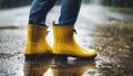 Close up yellow galoshes during the rainy day. Puddles on the street.