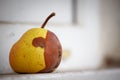 Close-up Yellow half-rotten apple on a blurred background of a white brick wall, selective focus Royalty Free Stock Photo