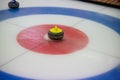 A close-up of a yellow-handled curling stone sits on ice in the center of the House Royalty Free Stock Photo