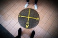 Close up yellow lines circle compass on the floor with legs feet of couple tourist traveler