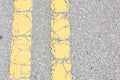 Close Up of Yellow Lines On Old Asphalt Road