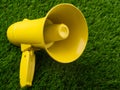 Close-up. Yellow megaphone on a green lawn. Minimalism. Rumors, fakes, false information. Rallies, demonstrations, pre-election