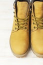 Close-up Yellow men`s work boots from natural nubuck leather on wooden white background. Trendy casual shoes, youth style. Concep Royalty Free Stock Photo