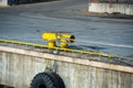 Close-up of yellow metallic mooring column or bollard on the edge of stone quay blue water background. Marine Bollard column with Royalty Free Stock Photo