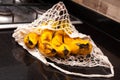 Close up of yellow overripe bananas in avoska. String bag with sweet organic ripening fruits on black kitchen table background.