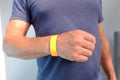 Close-up of yellow paper bracelet, check tape with entry number on hand of middle-aged european man, event ticket concept