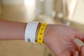 close-up of yellow plastic bracelet on the girl arm of child clinic patient, check tape with entry number on hand of Royalty Free Stock Photo