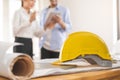 Close up yellow safety hard helmet. Asian, caucasian young engineer, architect two man are discussing construction to follow the Royalty Free Stock Photo