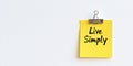 Close-Up of a Yellow Sticky Note with Live Simply in Handwriting, Isolated on White Background Royalty Free Stock Photo
